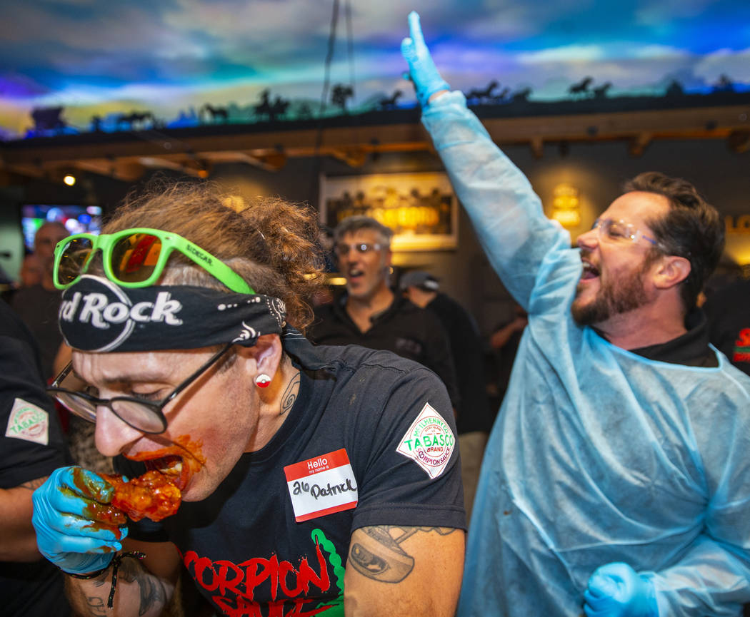 Competitor Patrick Gregory, left, digs into a wing while his judge Charles Anderson cheers him ...