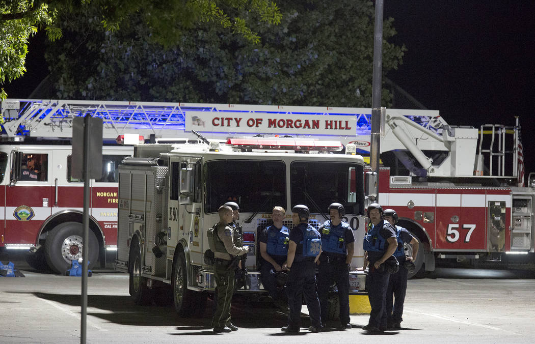 A police officer dressed in SWAT gear speaks with fire crews brought in from neighboring commun ...