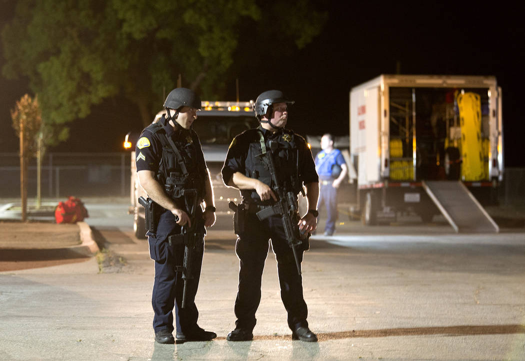 Police officers dressed in SWAT gear stand guard at the first aid center at Gilroy High School ...