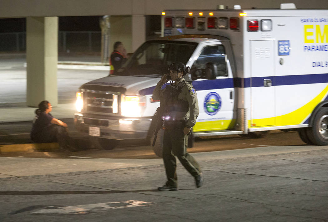 A police officer dressed in SWAT gear walks through the first aid center at Gilroy High School ...