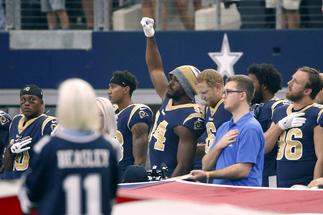 Then-Los Angeles Rams linebacker Robert Quinn (94) raises his fist during the playing of the na ...