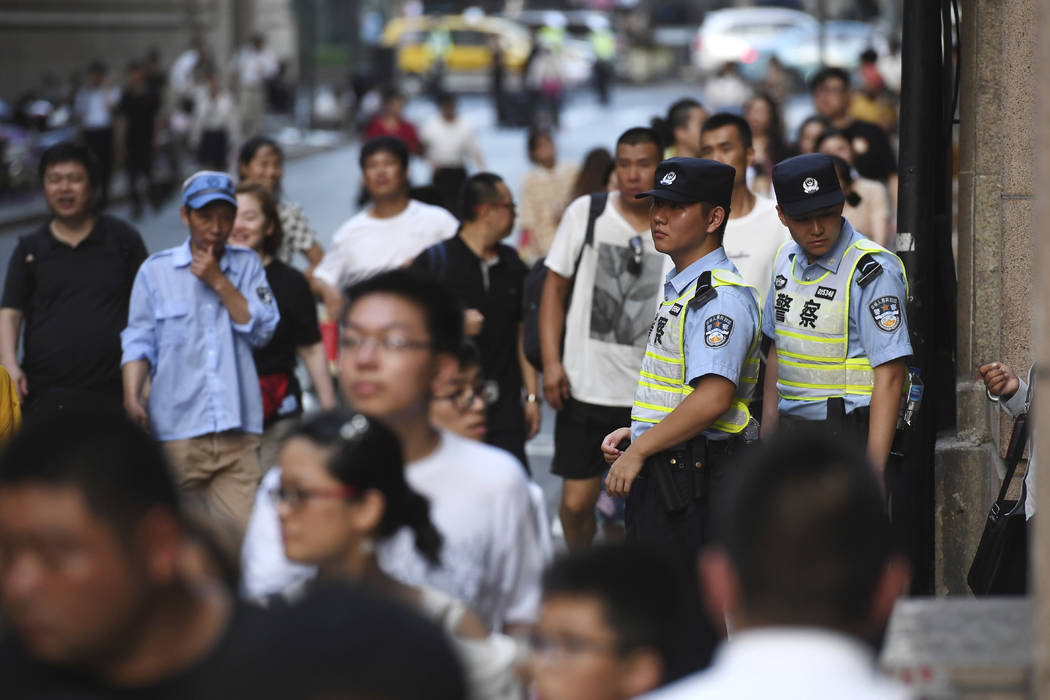 Police keep watch over the crowds walking past an entrance to the Peace Hotel before the arriva ...