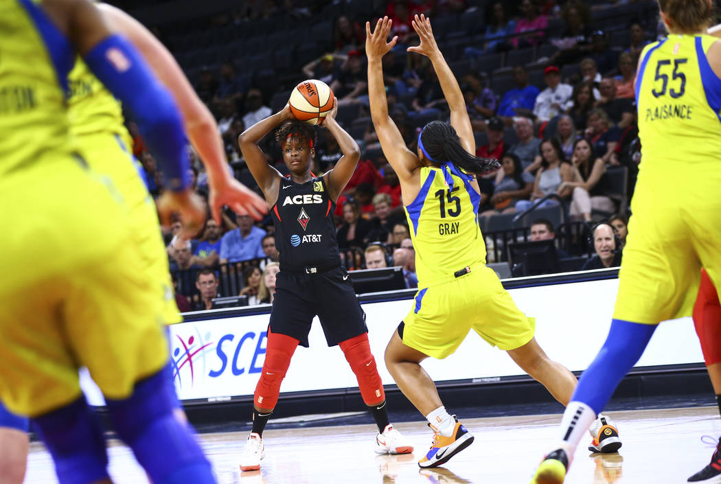 Las Vegas Aces' Sugar Rodgers looks to pass the ball under pressure from Dallas Wings' Allisha ...