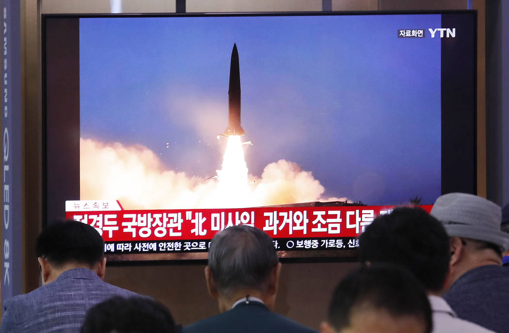 People watch a TV showing a file image of North Korea's missile launch during a news program at ...