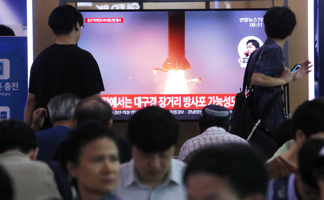 People watch a TV showing a file image of North Korea's missile launch during a news program at ...