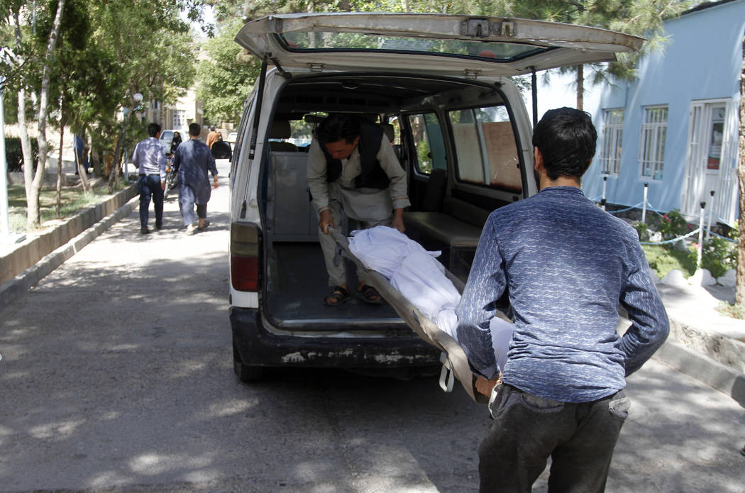 Afghans carry the dead body of a victim in a hospital after a roadside bomb on the main highway ...