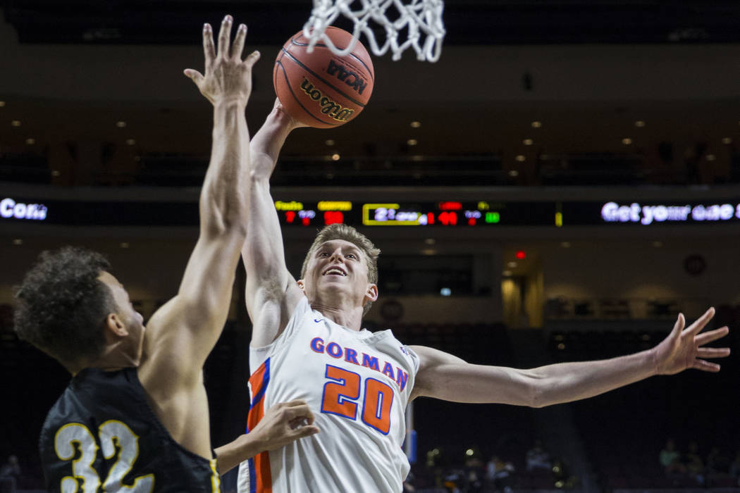 Bishop Gorman junior guard Noah Taitz (20) drives over Clark senior forward Ian Alexander (32) ...