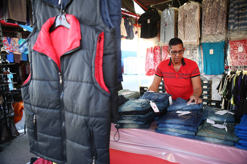 Vendor Adrian Reyes organizes merchandise at his clothing booth at the Broadacres Marketplace i ...