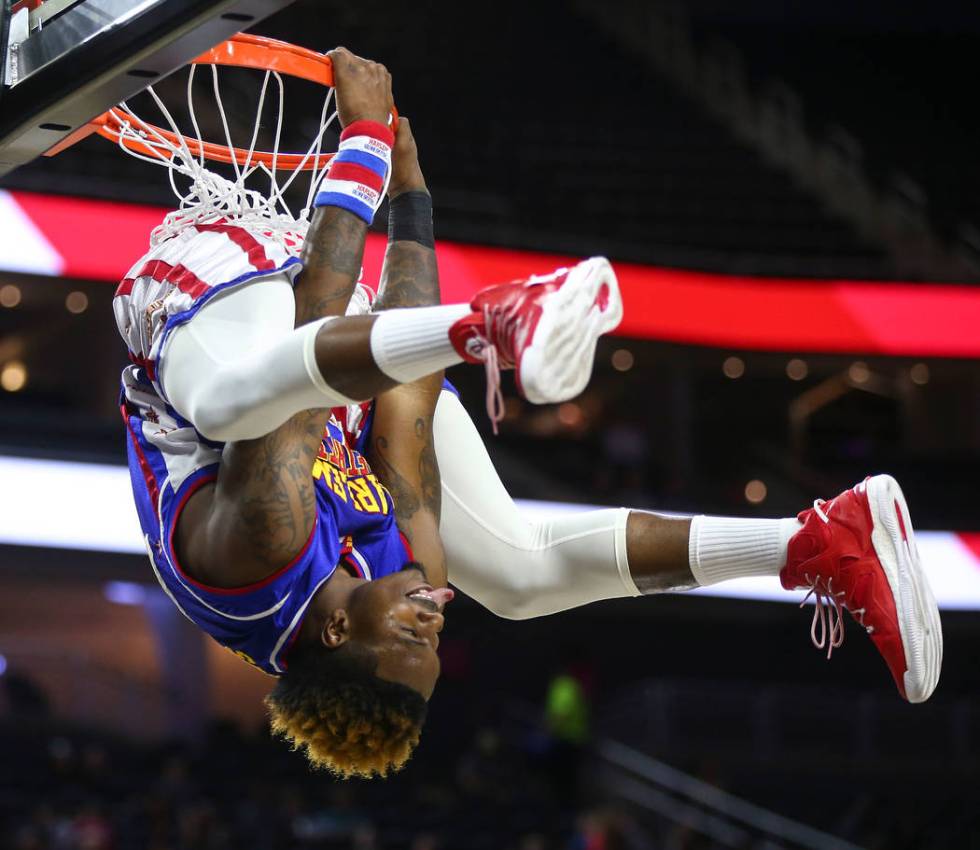 Harlem Globetrotters forward Angelo "Spider" Sharpless (42) hangs from the basket aft ...