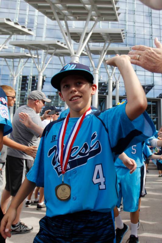 Mountain Ridge Little League player Drew Laspaluto (4), high fives fans as the team leaves for ...