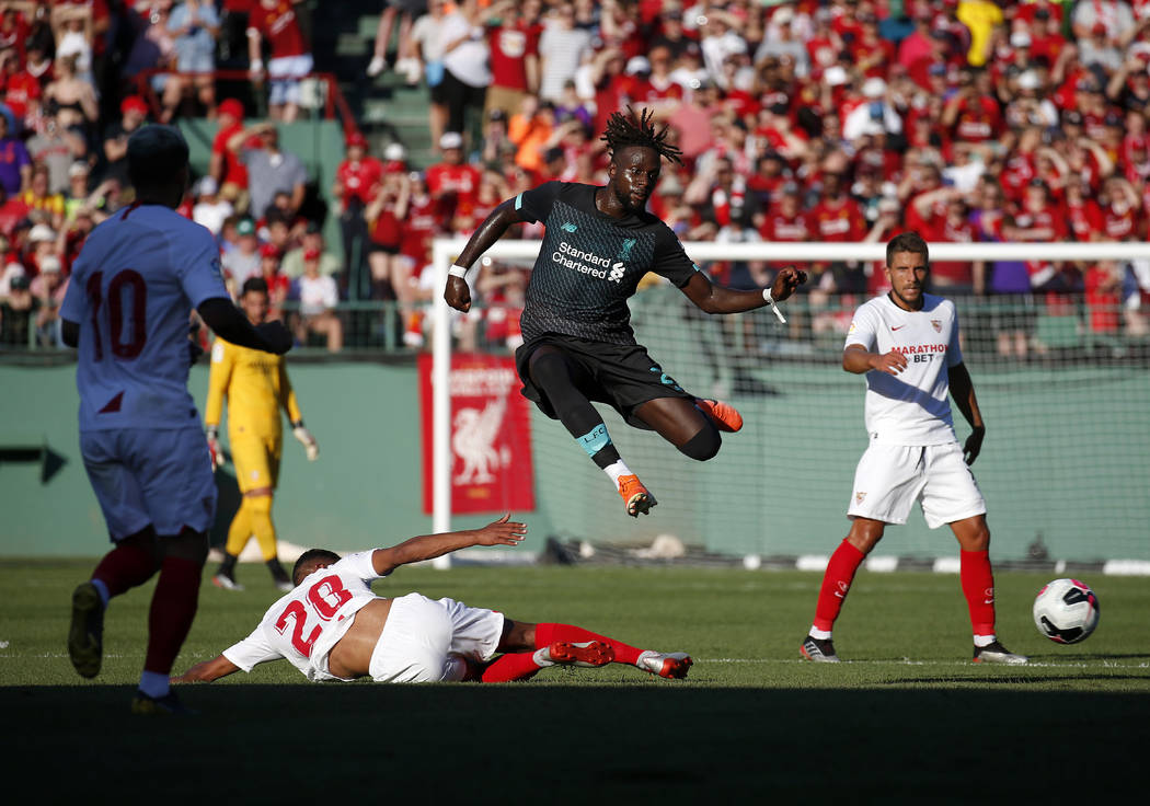 Liverpool's Divock Origi, center, leaps over Sevilla's Diego Carlos Santos Silva (20) during th ...