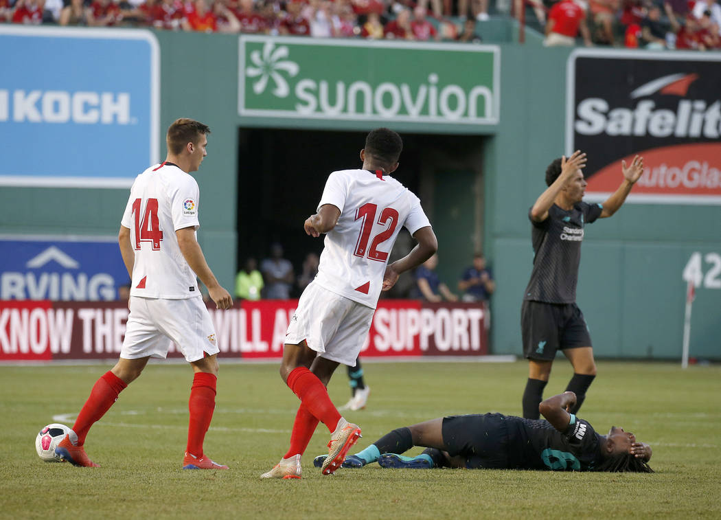 Liverpool's Yasser Larouci reacts on the turf as Sevilla players Jules Kounde (12) and Maximill ...