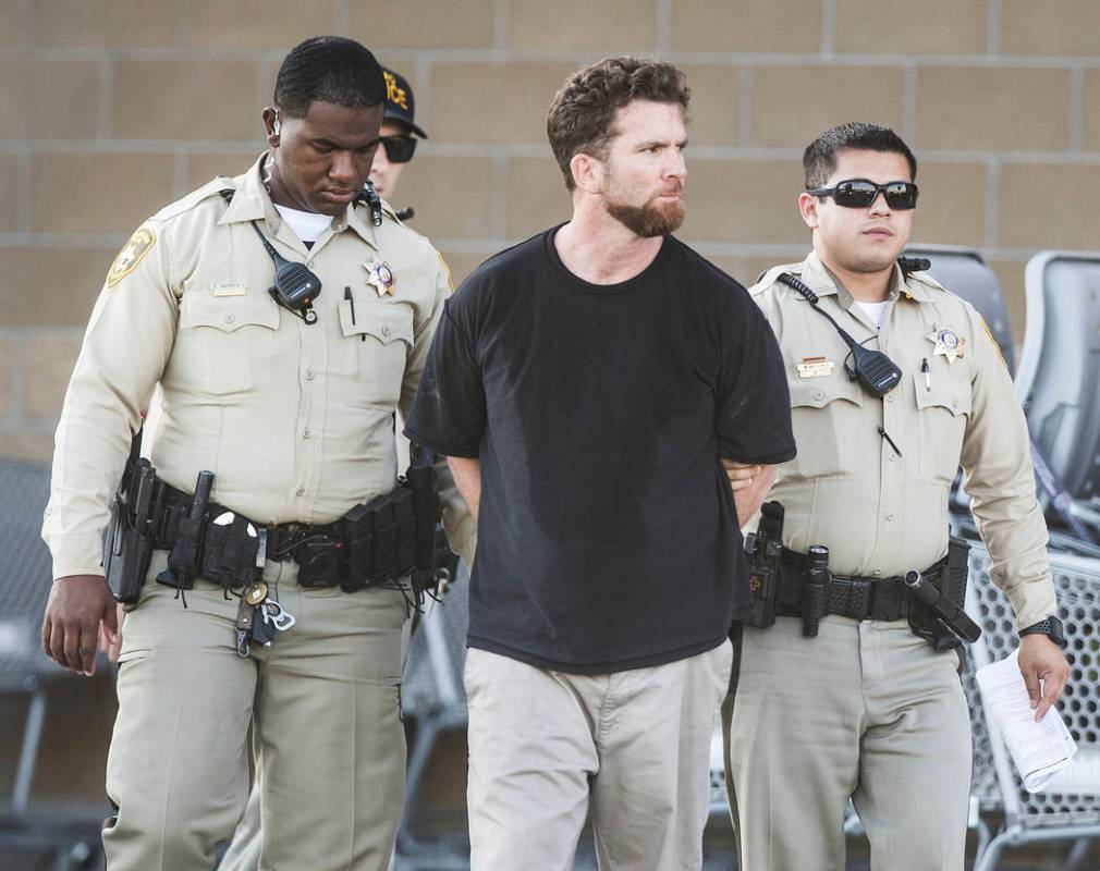 A man is escorted by Las Vegas police officers at the Smith's Marketplace, at 9710 West Skye Ca ...