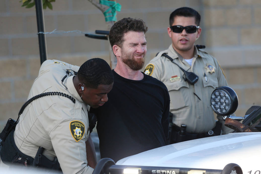 A man is escorted by Las Vegas police officers at the Smith's Marketplace, at 9710 West Skye Ca ...