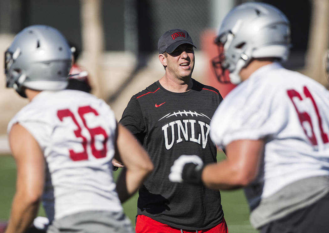 UNLV offensive coordinator Garin Justice, middle, coaches up the Rebels during the first day of ...