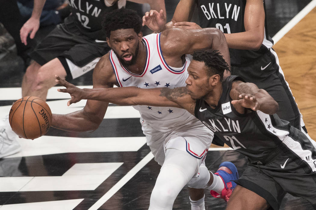 Philadelphia 76ers center Joel Embiid passes the ball around Brooklyn Nets guard Treveon Graham ...