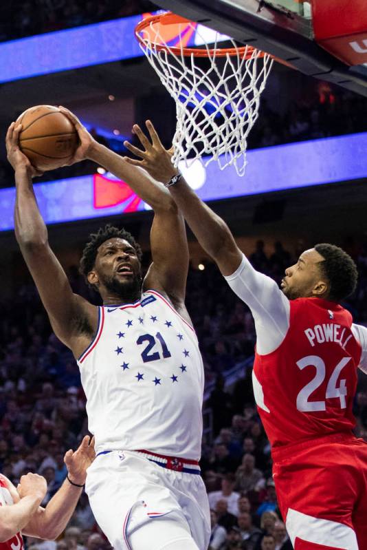 Philadelphia 76ers' Joel Embiid, left, goes up for the shot against Toronto Raptors' Norman Pow ...