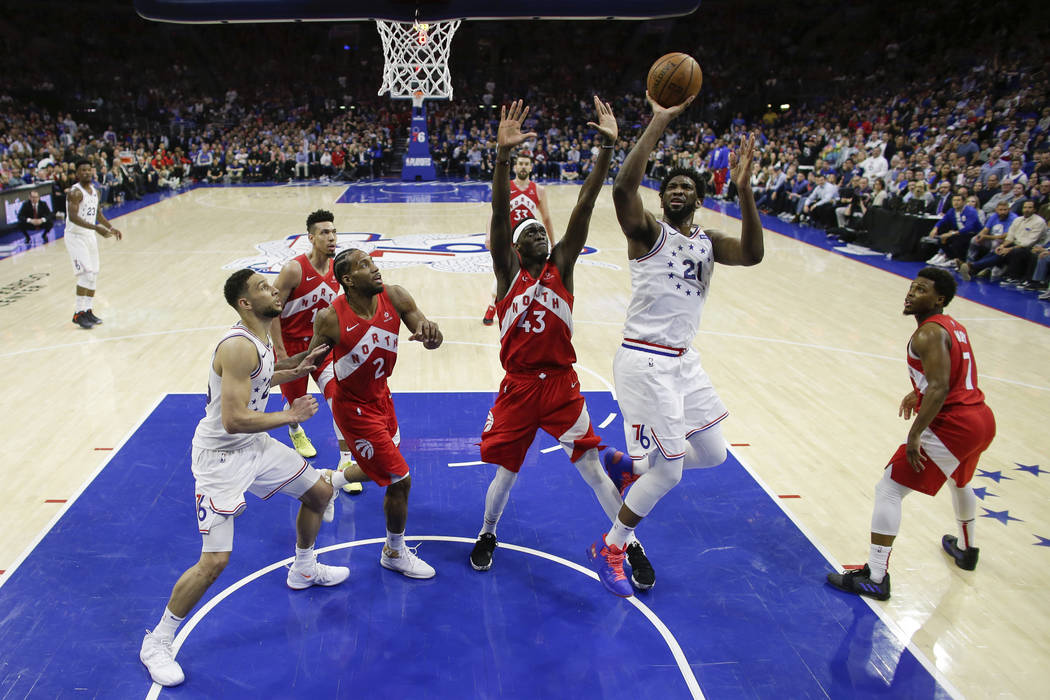 Philadelphia 76ers' Joel Embiid, center right, puts up the shot against Toronto Raptors' Pascal ...