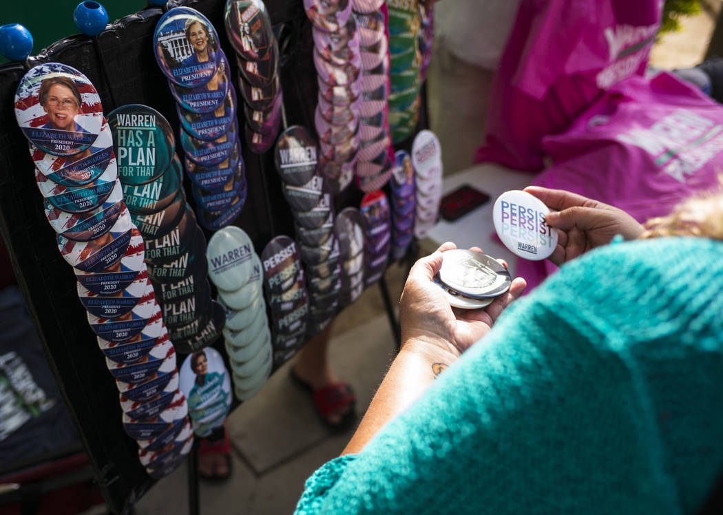 A supporter of Democratic presidential candidate Sen. Elizabeth Warren, D-Mass., looks at pins ...