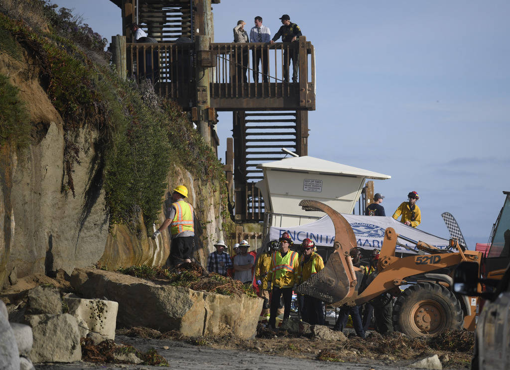 Search and rescue personnel work at the site of a cliff collapse at a popular beach Friday, Aug ...