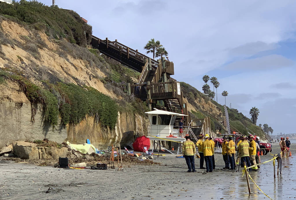 Lifeguards and search and rescue personnel work at the site of a cliff collapse at a popular be ...