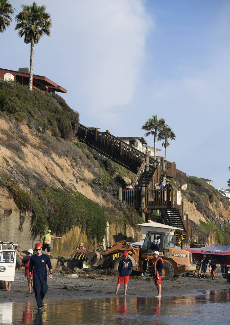 Search and rescue personnel work at the site of a cliff collapse at a popular beach Friday, Aug ...