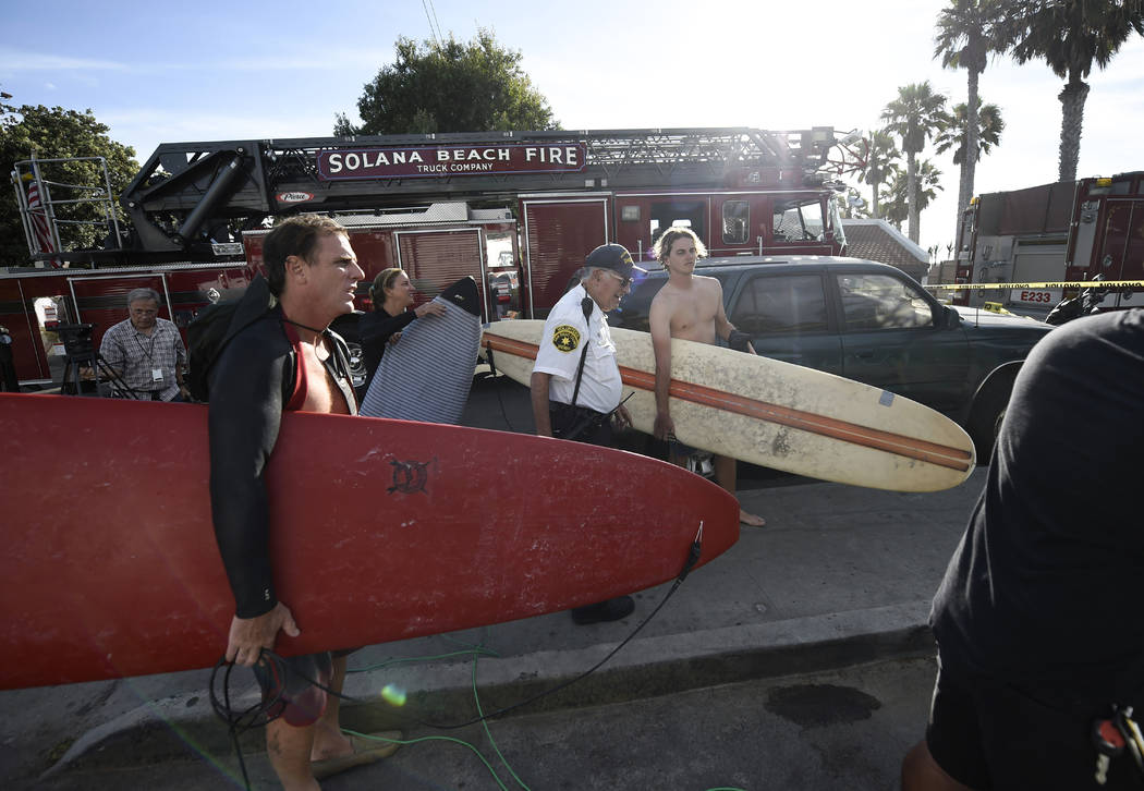 Surfers wait at the top of the stairs above the site of a cliff collapse at a popular beach Fri ...