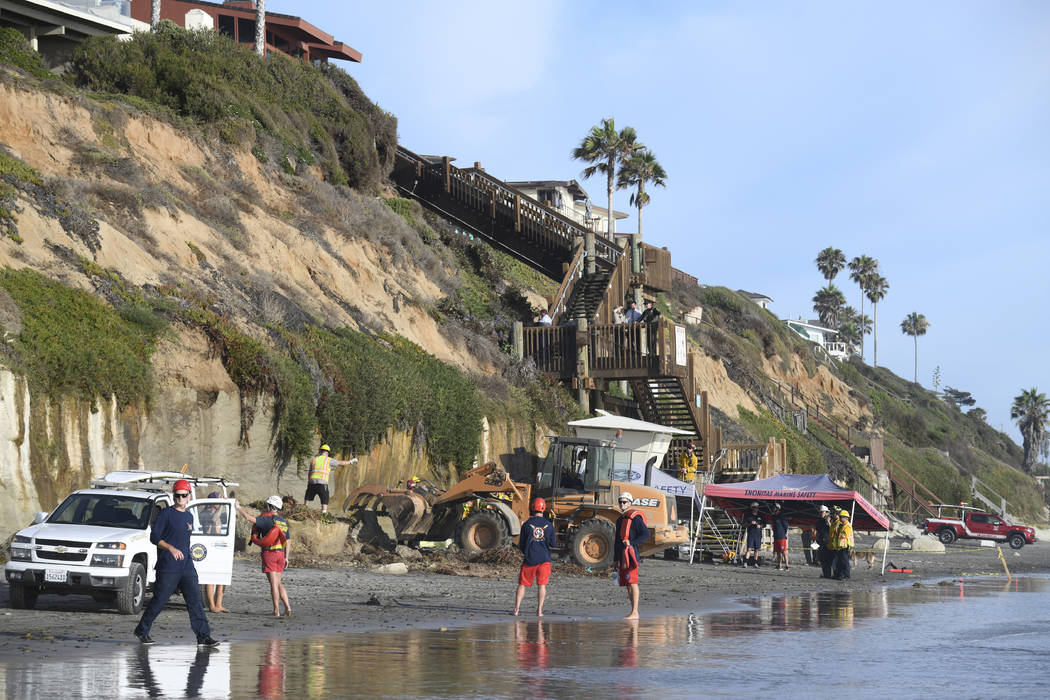 Search and rescue personnel work at the site of a cliff collapse at a popular beach Friday, Aug ...