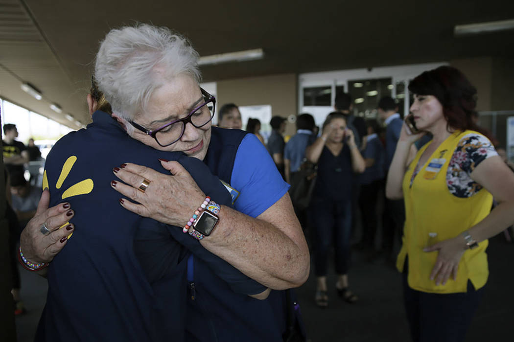 Walmart employees comfort one another after an active shooter opened fire at the store in El Pa ...