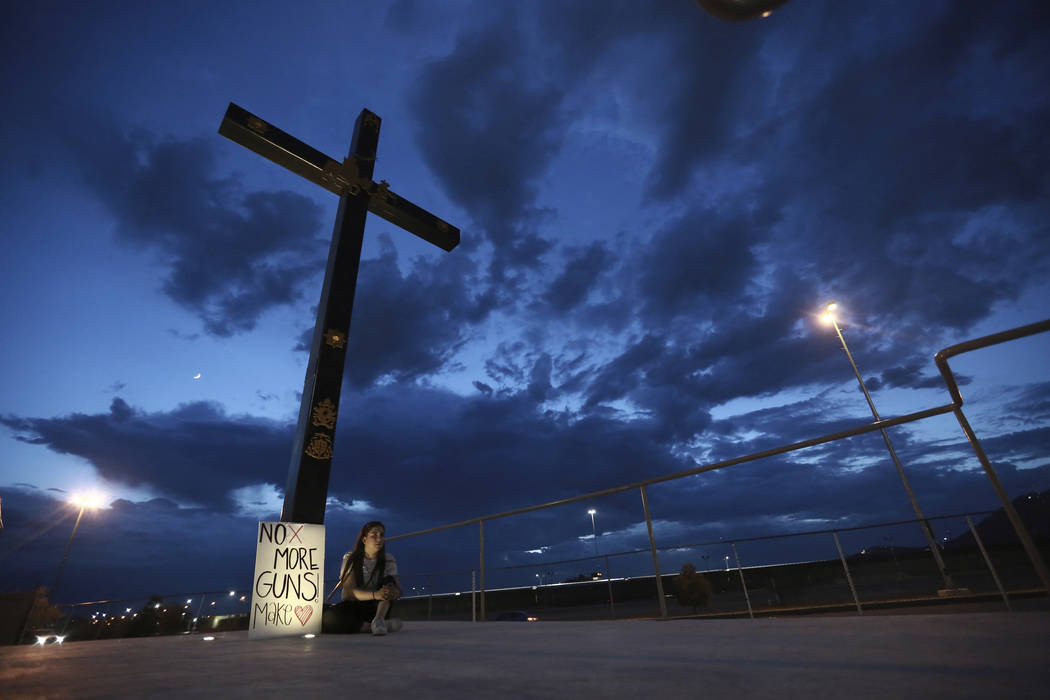 A woman sits next to a sign with a message that reads: ¨No More Guns! Make Love¨, in ...