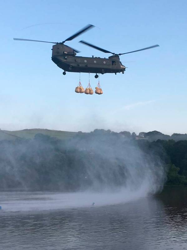 In this image released by the Ministry of Defence, an RAF Chinook helicopter flies in sandbags ...