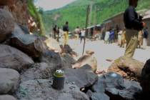 Police officers stand guard next to a munition fired by Indian forces on Nosehri village on the ...