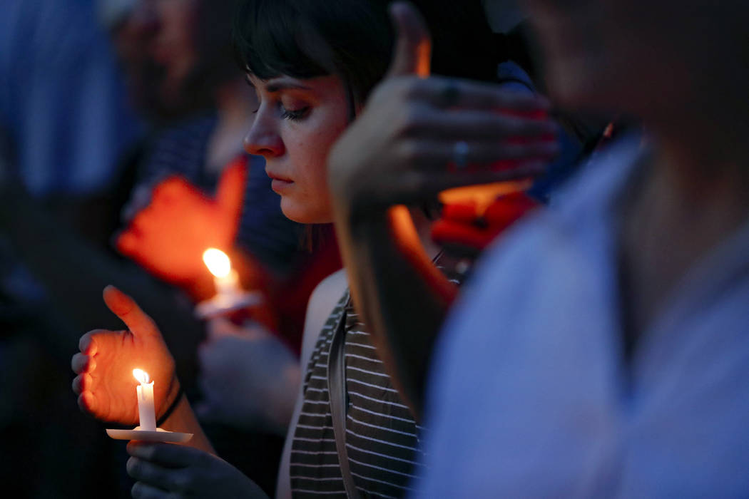 Mourners bow their heads in prayer as they gather for a vigil at the scene of a mass shooting, ...