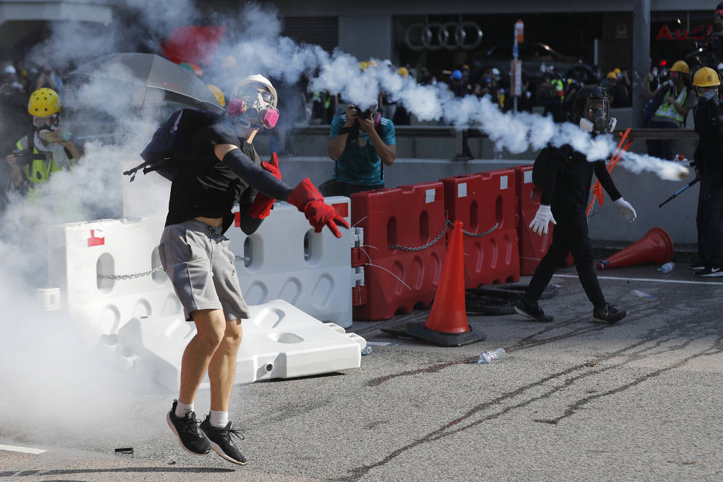 A protester throws back a tear gas canister in Hong Kong on Monday, Aug. 5, 2019. Droves of pro ...