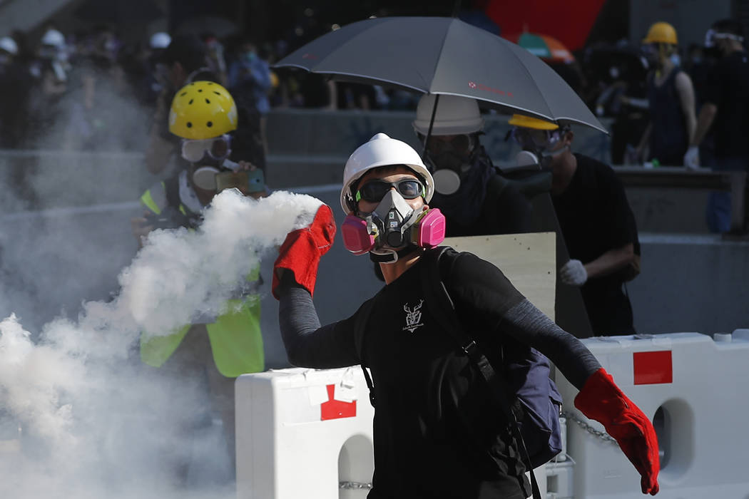 A protester throws back a tear gas canister in Hong Kong on Monday, Aug. 5, 2019. Droves of pro ...