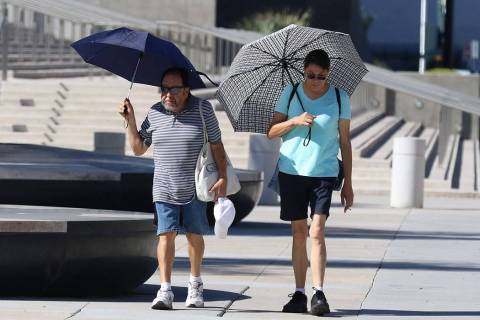 Pedestrians hold umbrellas to protect themselves from sun as they walk along Las Vegas Boulevar ...