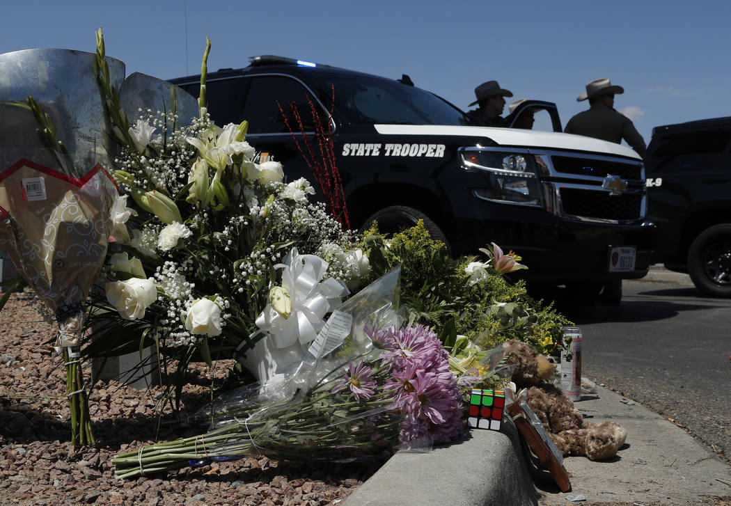 Flowers adorn a makeshift memorial near the scene of a mass shooting at a shopping complex Sund ...