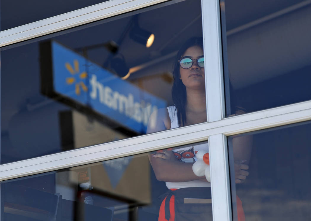 A restaurant employee looks at the scene of a mass shooting at a shopping complex Sunday, Aug. ...