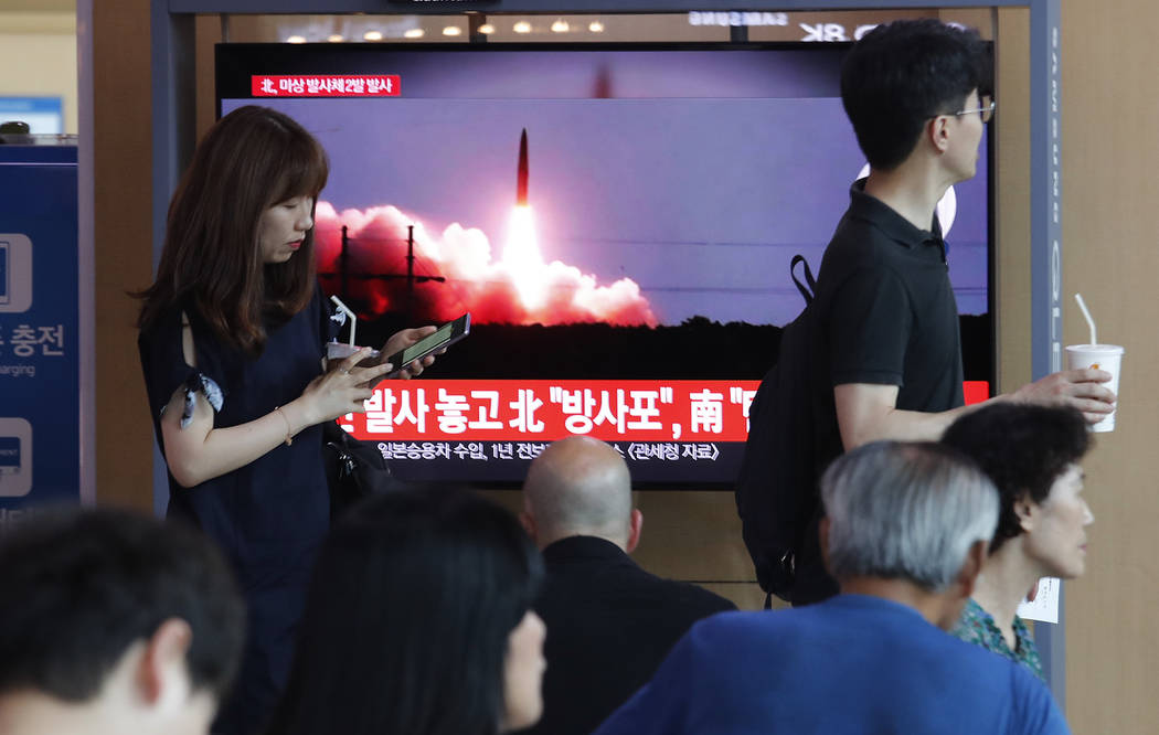 People watch a TV showing a file image of North Korea's missile launch during a news program at ...