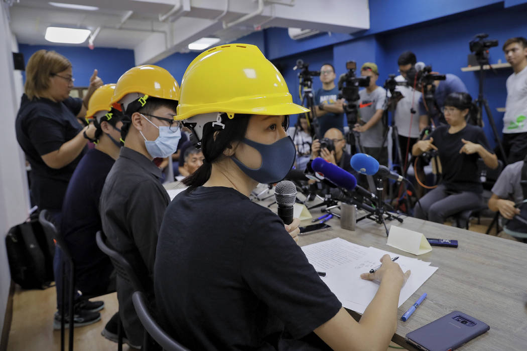 Protesters from right, Mary Tsang, Linus Kim and Jerry Chan listen to a question from a reporte ...