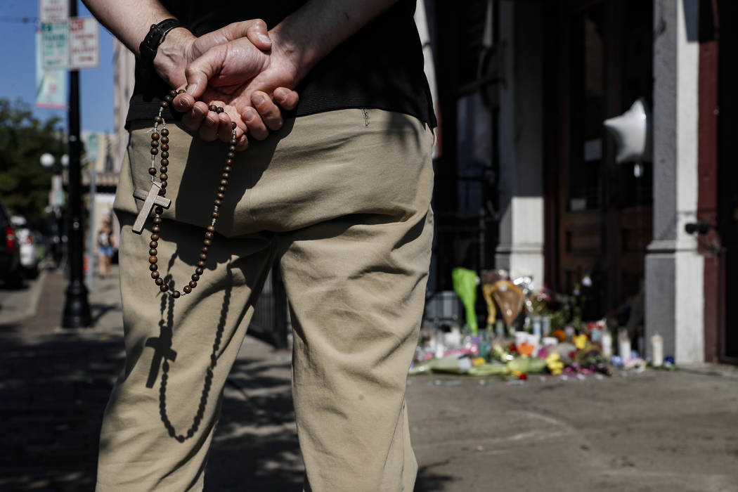 A mourner prays his rosary beads beside a memorial outside Ned Peppers bar that was the scene o ...