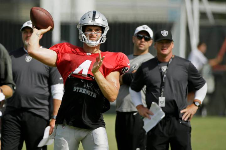 Oakland Raiders quarterback Derek Carr throws as head coach Jon Gruden, right, looks on during ...