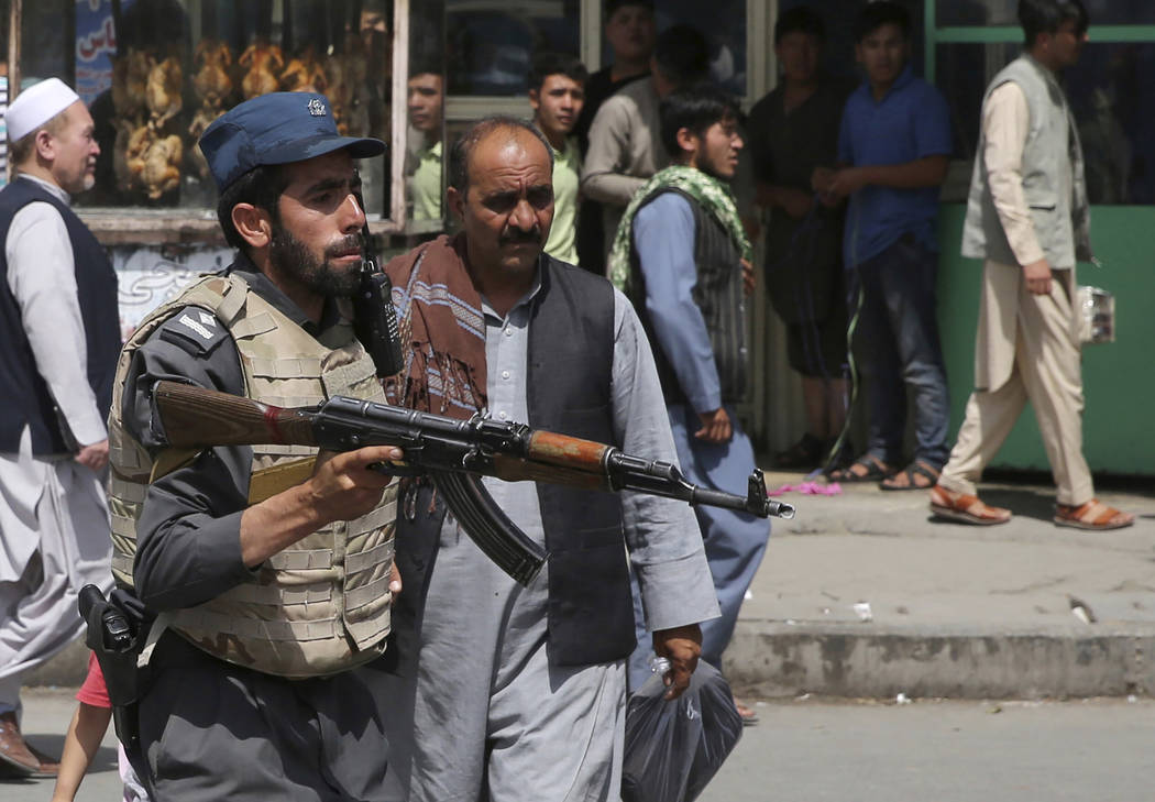 An Afghan policeman stands guard after an explosion near the police headquarters in Kabul, Afgh ...