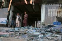 Afghans stand near a damaged shop after an explosion in Kabul, Afghanistan, Wednesday, Aug. 7, ...