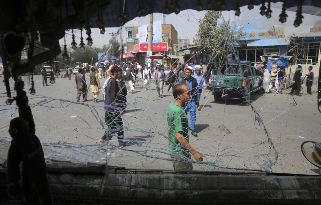 Afghans are seen through a shattered glass of a transport bus broken after an explosion in Kabu ...