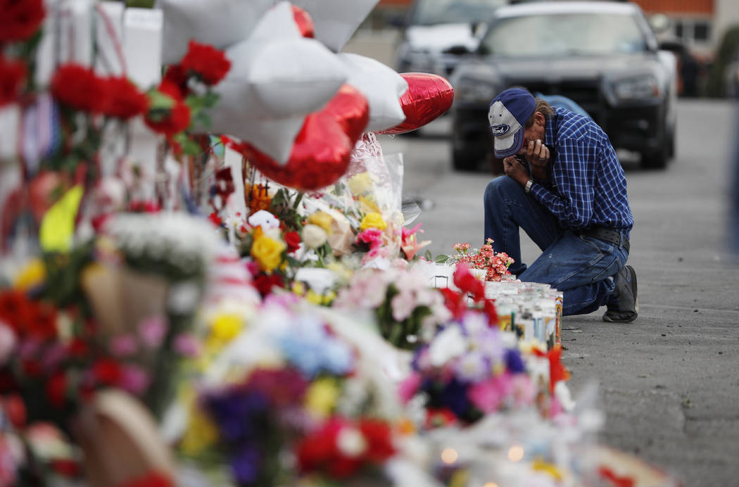 A man cries beside a cross at a makeshift memorial near the scene of a mass shooting at a shopp ...