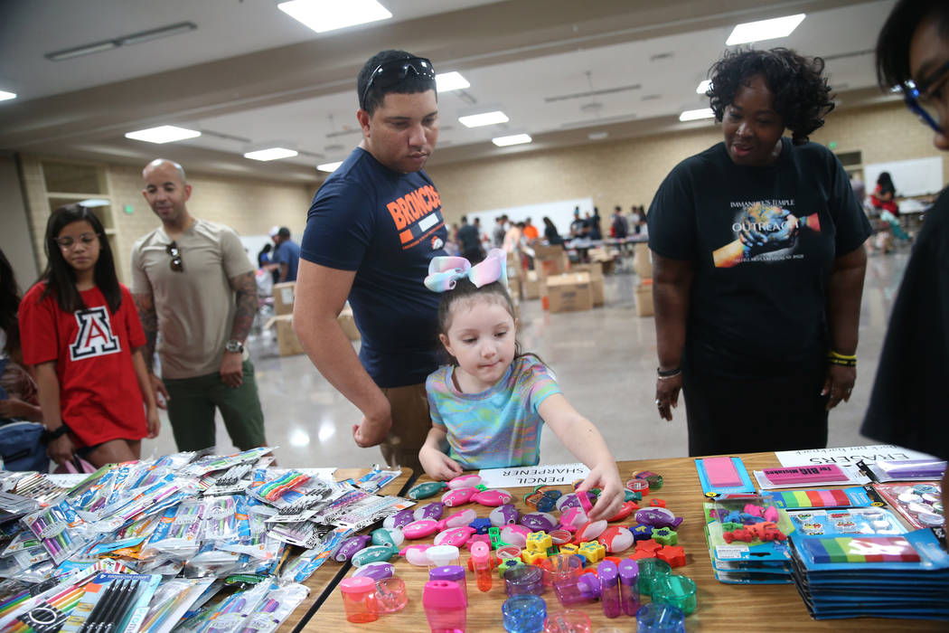 Volunteer LaShuna Proctor, right, assists Kyle Hammond and his daughter Lily, 5, with selecting ...