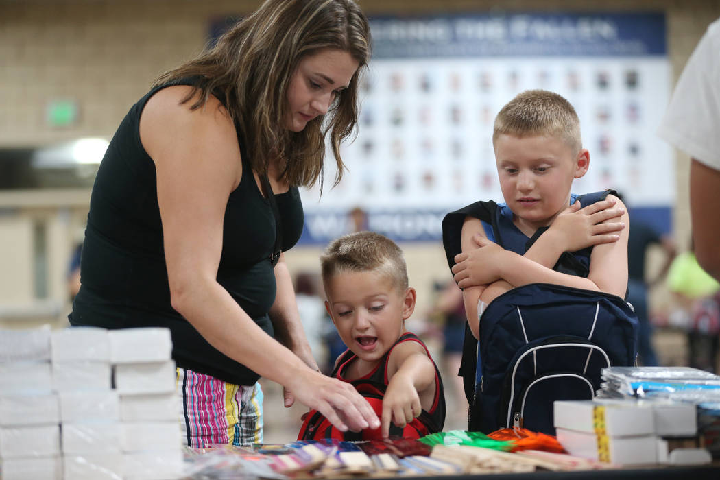 Kimberly Weller, from left, with her sons Owen, 6, and Brayden, 8, select free school supplies ...