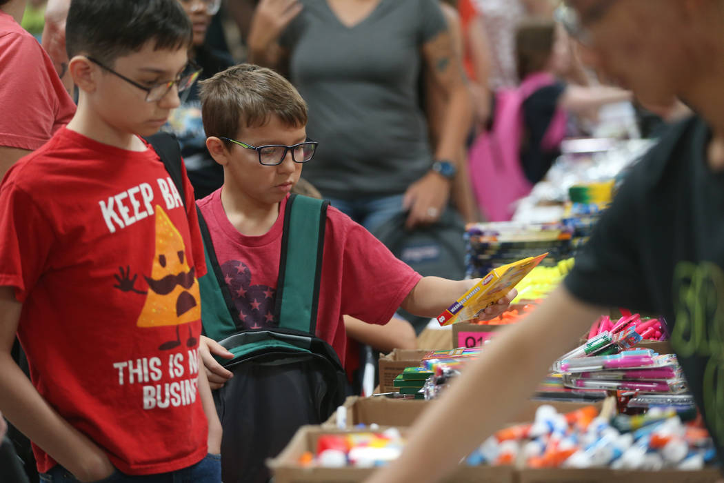 Lucas Stockmann, 13, left, and his brother Sebastian, 8, select free school supplies during an ...