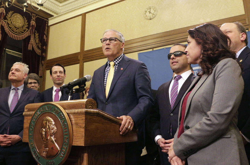 FILE - In this April 29, 2019, file photo, Gov. Jay Inslee, surrounded by Democratic lawmakers ...